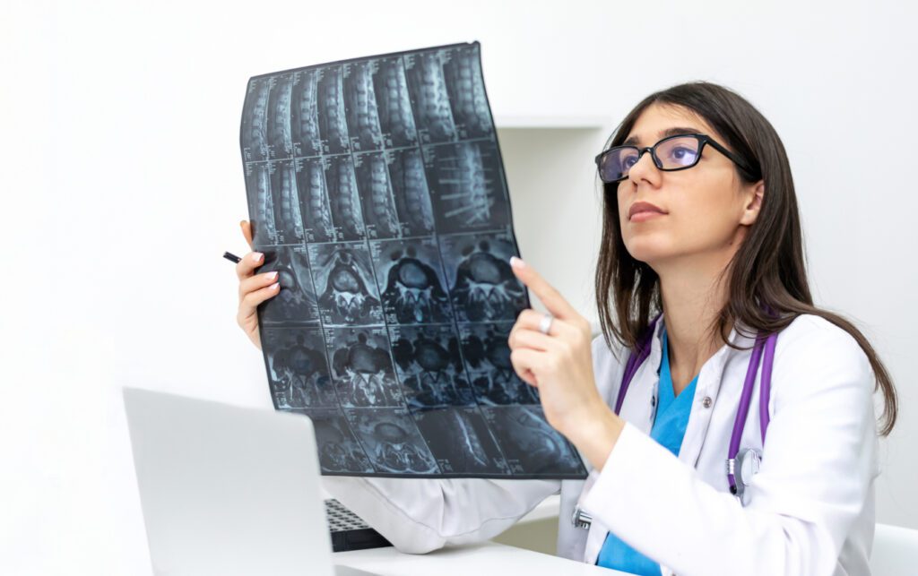 Doctor examining spinal X-ray in office.